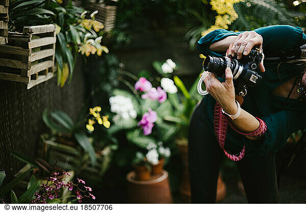 Woman photographs flowers in garden with DSLR camera