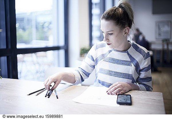 Woman picking up pencil to draw