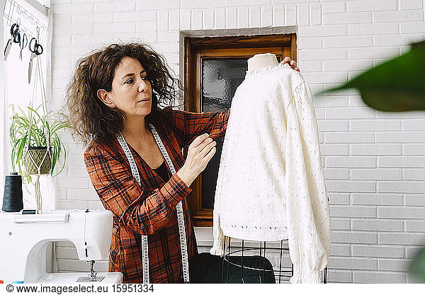 Woman pinning top on dress form at home