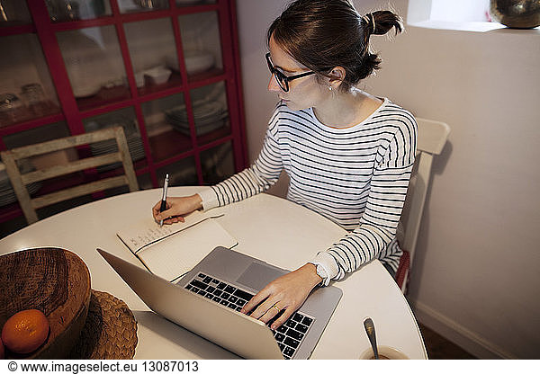 Woman planning while working on laptop at home