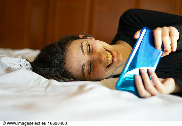 Woman playing a mobile game in bed.