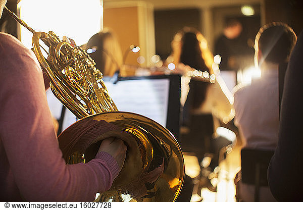 Woman playing french horn in orchestra