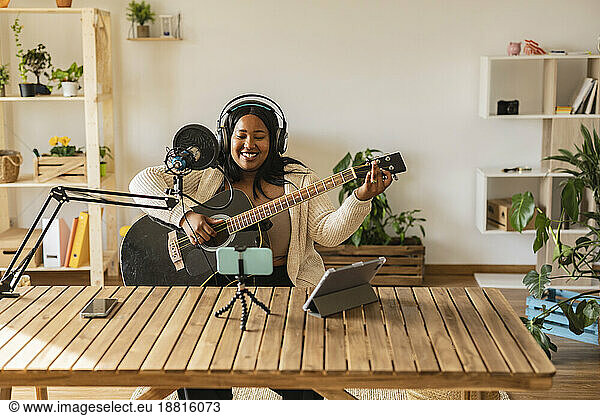 Woman playing guitar and podcasting at home