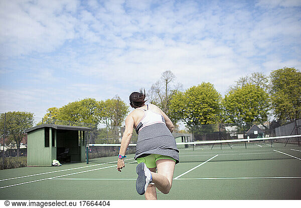 Woman playing tennis on sunny tennis court