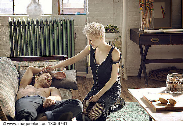 Woman playing with man's hair while kneeling on floor