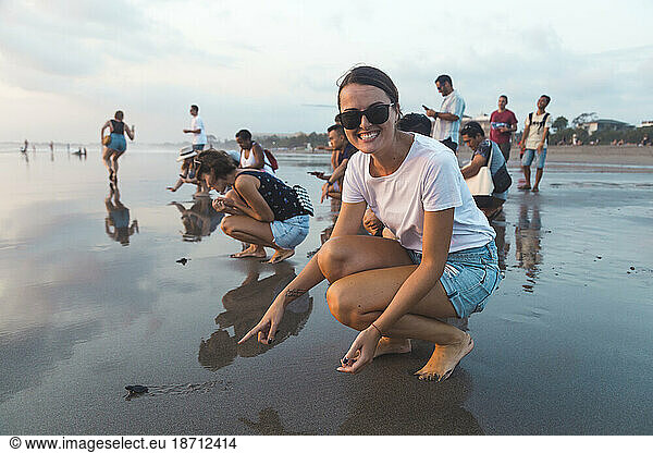 Woman pointing at baby turtle on beach  Seminyak  Bali  Indonesia