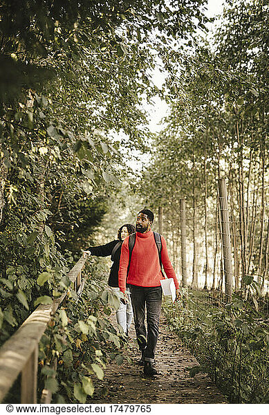 Woman pointing at plants while walking with boyfriend in forest