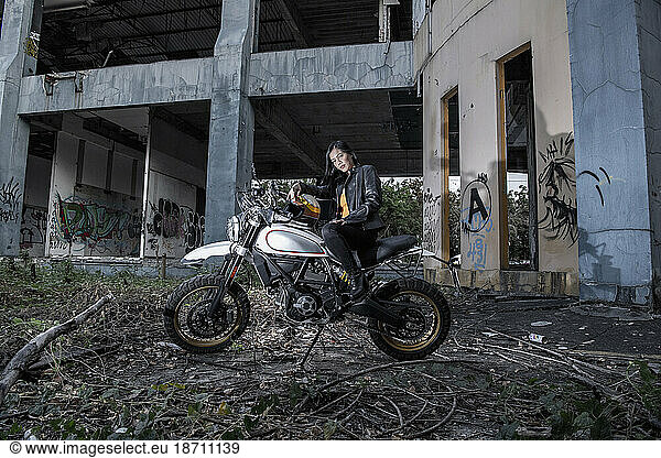 Woman posing on scrambler type motorcycle in abandoned building