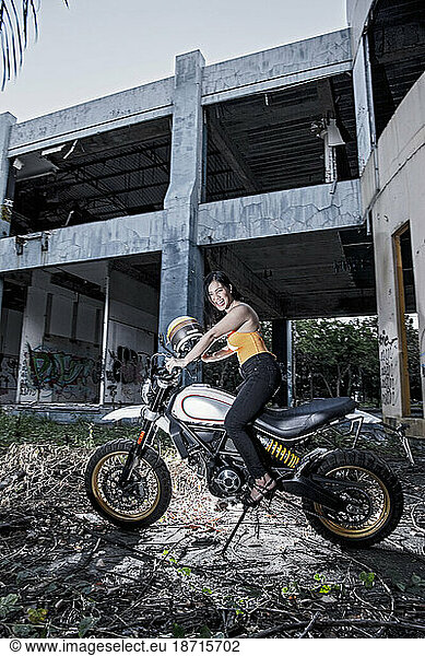 Woman posing on scrambler type motorcycle in abandoned building
