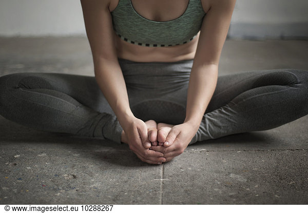 Woman practicing cobbler pose in yoga studio  Munich  Bavaria  Germany