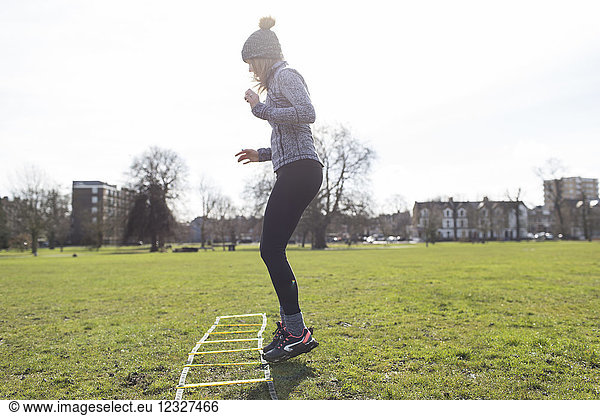 Woman practicing speed ladder drill in sunny park