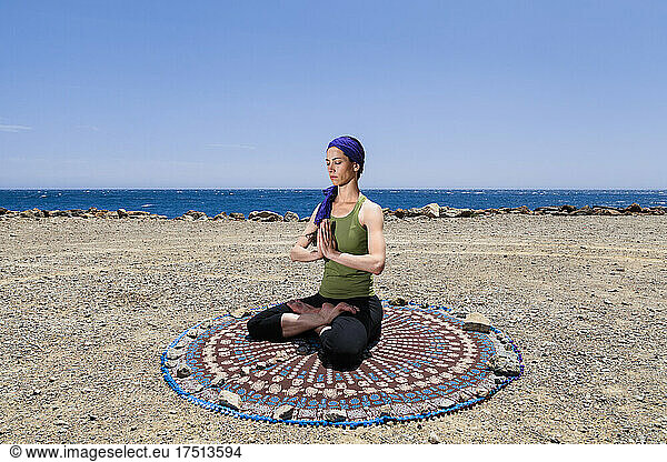 Woman practicing yoga and meditating at beach