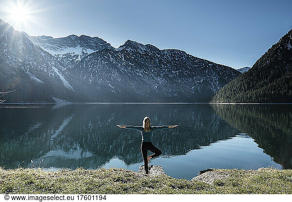 Woman practicing yoga at Lake Plansee  Ammergau Alps  Reutte  Tyrol  Austria