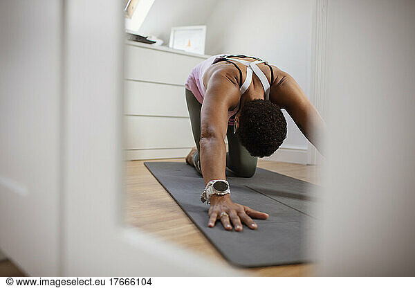 Woman practicing yoga child's pose on exercise mat