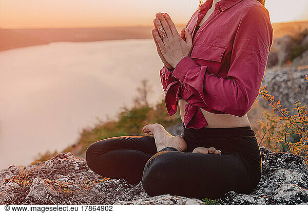 Woman practicing yoga  namaste gratitude mudra alone on high mountain