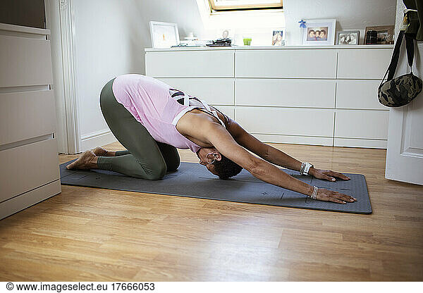 Woman practicing yoga on exercise mat at home