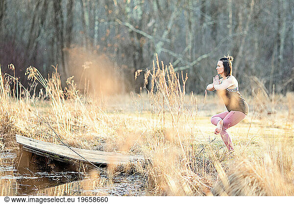 Woman practicing yoga outside in a meadow with tall golden grass