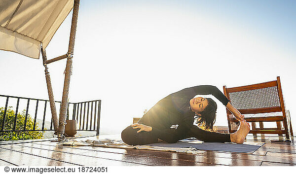 woman practising yoga on wooden deck above Chiang Rai