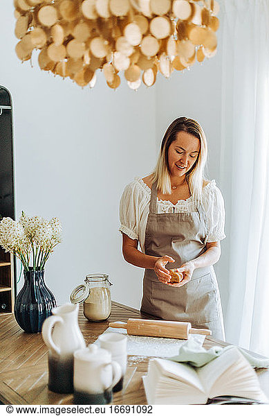 Woman preparing dough for cookies standing at domestic kitchen