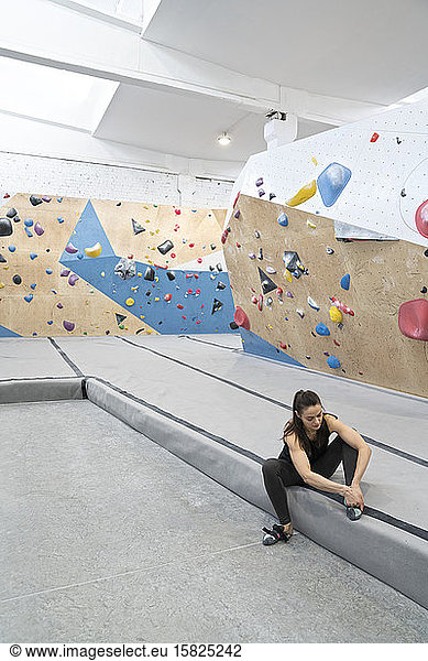 Woman preparing for climbing on the wall putting on shoes