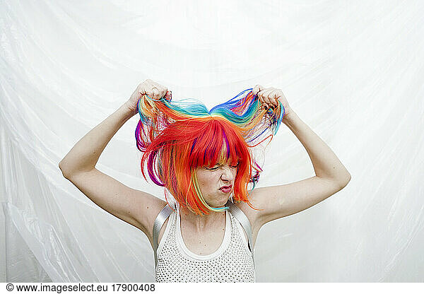 Woman pulling hair in front of plastic backdrop