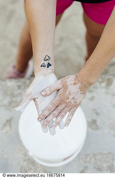 Woman putting chalk in her hands before practicing crossfit.