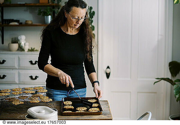 woman putting freshly baked cookies on cooling rack
