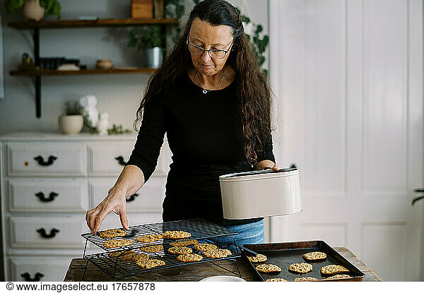 woman putting freshly baked cookies on cooling rack