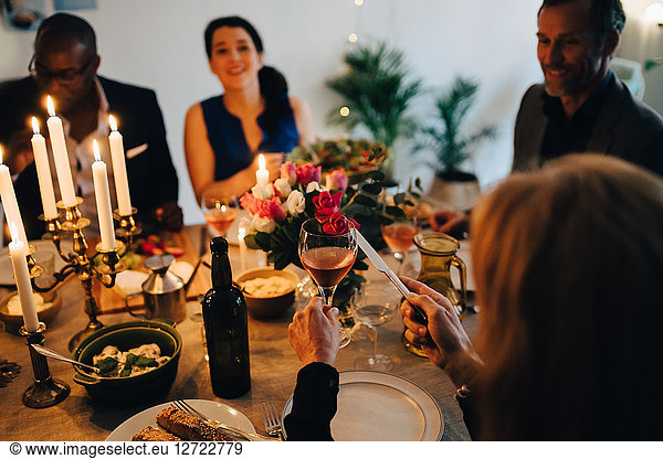 Woman raising toast with wineglass in dinner party at home