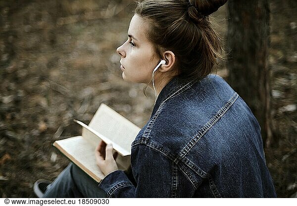 Woman reading a book sitting in the forest