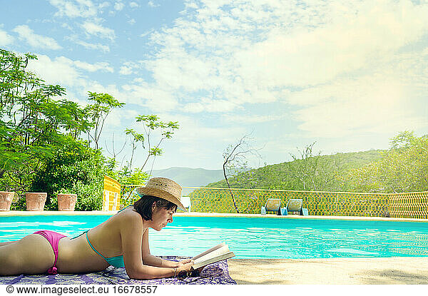 Woman reading and relaxing in luxury swimming pool. Relaxing vacation