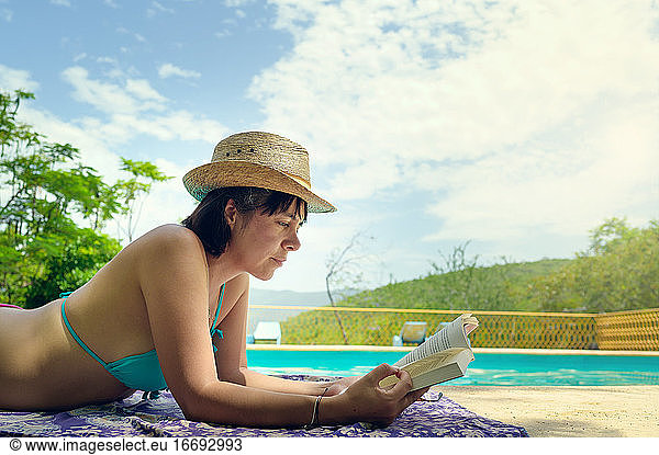 Woman reading and relaxing in luxury swimming pool. Relaxing vacation