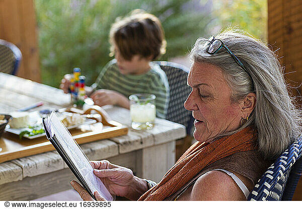 Woman reading file outside on terrace at sunset.