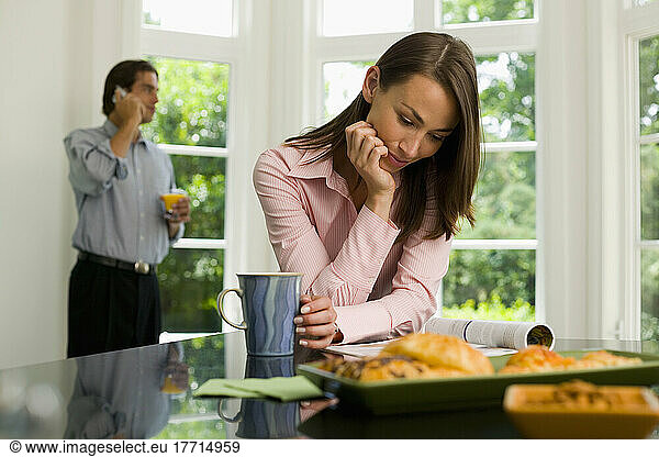 Woman Reading  Man On Cellphone In Kitchen
