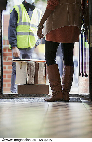 Woman receiving packages from delivery person at front door