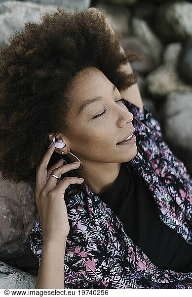 Woman relaxing and listening to music through wireless In-ear headphones