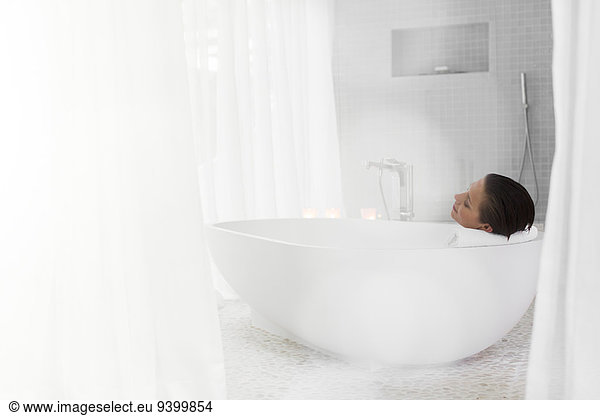 Woman relaxing in bath in modern bathroom