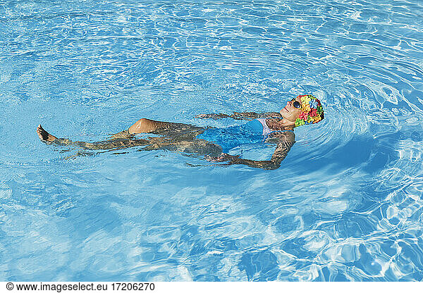 Woman relaxing in clear blue swimming pool