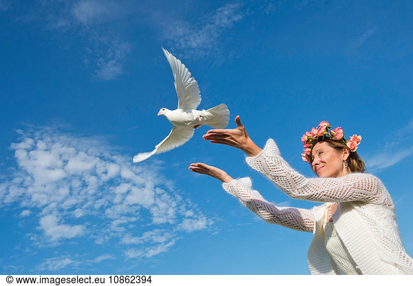 Woman releasing white dove into sky