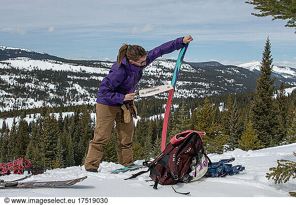 Woman removes skins from her splitboard in the Colorado Backcountry