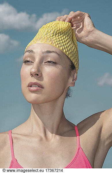Woman removing yellow swimming cap during sunny day