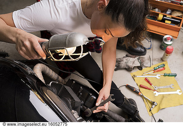 Woman repairing motorbike