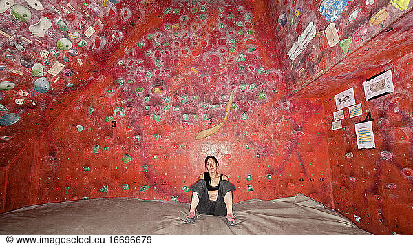 woman resting on bouldering mat at indoor climbing gym
