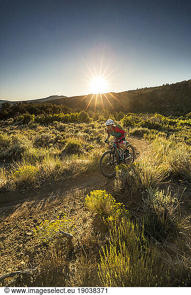 Woman riding a mountain bike on a trail just before sunset.