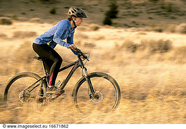 Woman riding downhill mountain biking during sunset