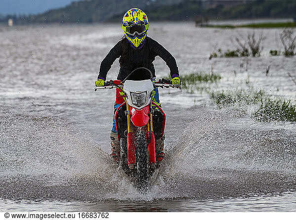woman riding her dirt-bike through a lake near Pak Chong / Thailand