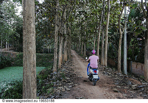 Woman riding scooter on forest road  Pai  Mae Hong Soon  Thailand
