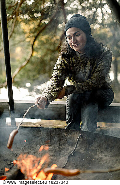 Woman roasting food over campfire during camping