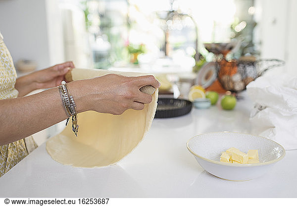 Woman rolling pie crust dough in kitchen