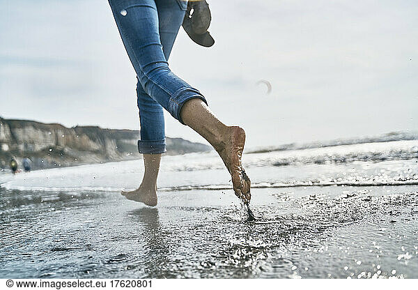 Woman running barefoot in sea at vacation